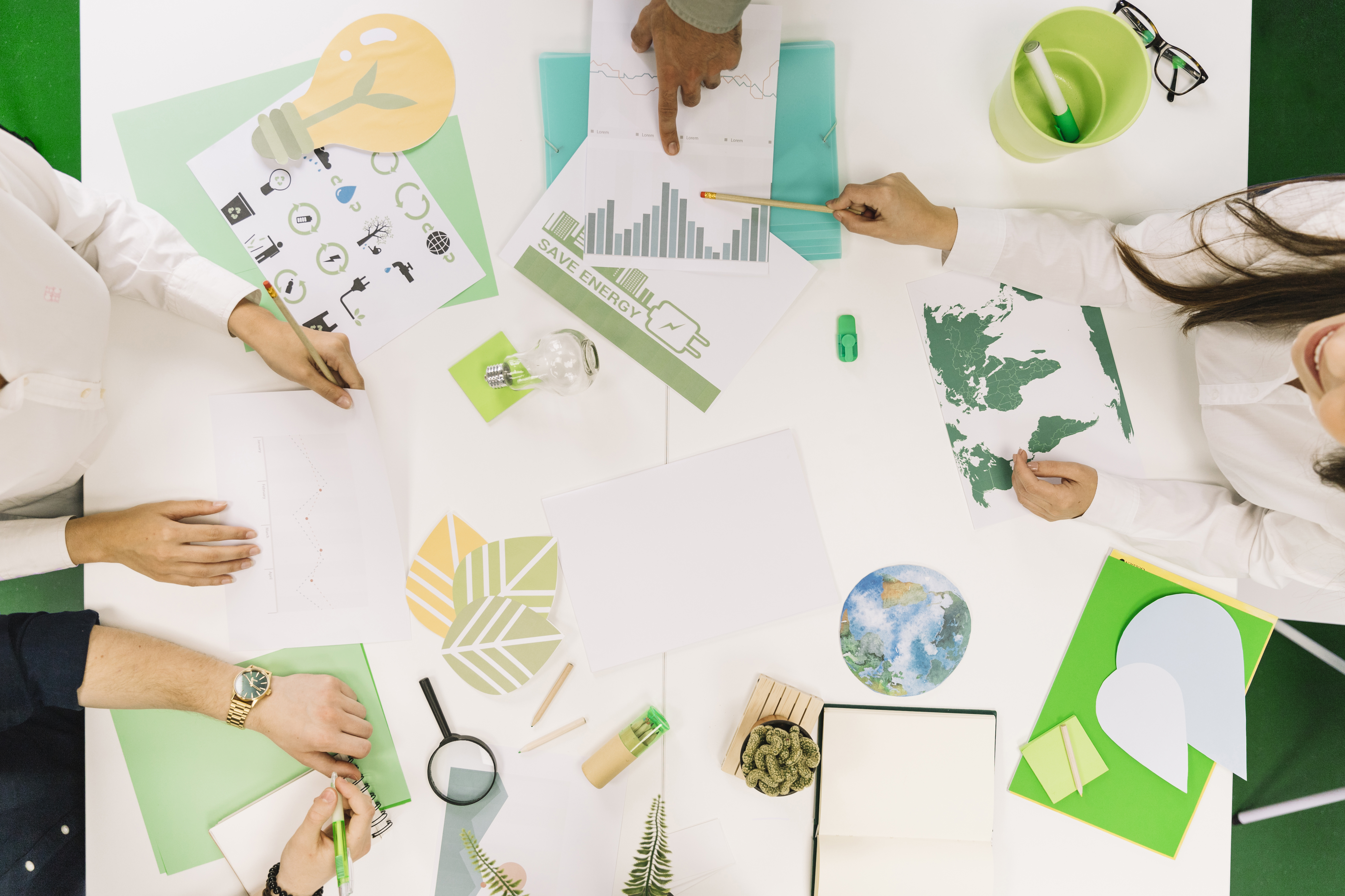 businesspeople-working-on-graph-with-various-natural-resources-icon-on-desk
